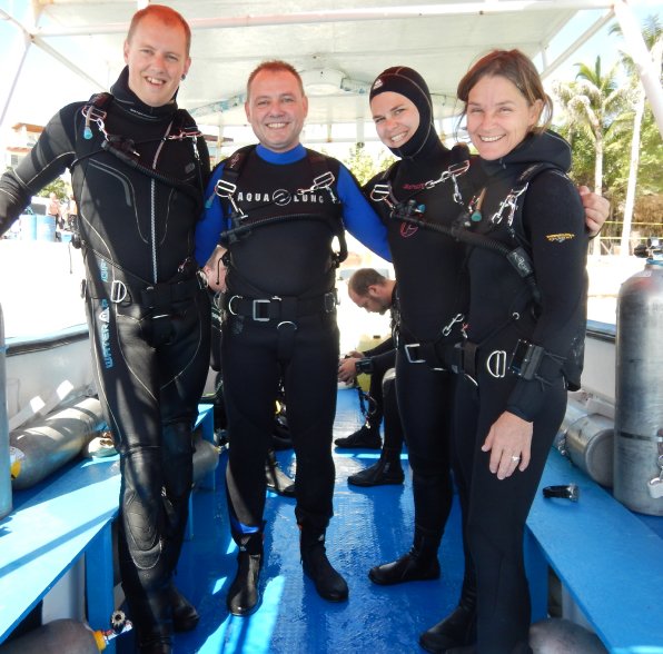 Vier zertifizierte Sidemount-Taucher lächeln auf einem Boot in Playa del Carmen, bereit für geführte Ozean- und Höhlentauchgänge mit Cenote Dive Tour.<br />
